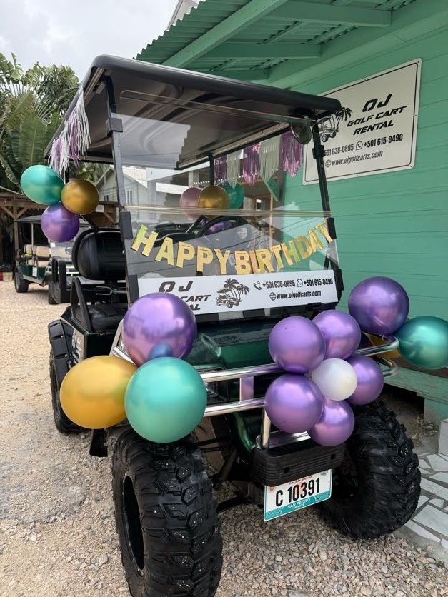 Dark green golf cart with Happy Birthday banner and purple teal gold chrome balloon clusters in San Pedro Belize