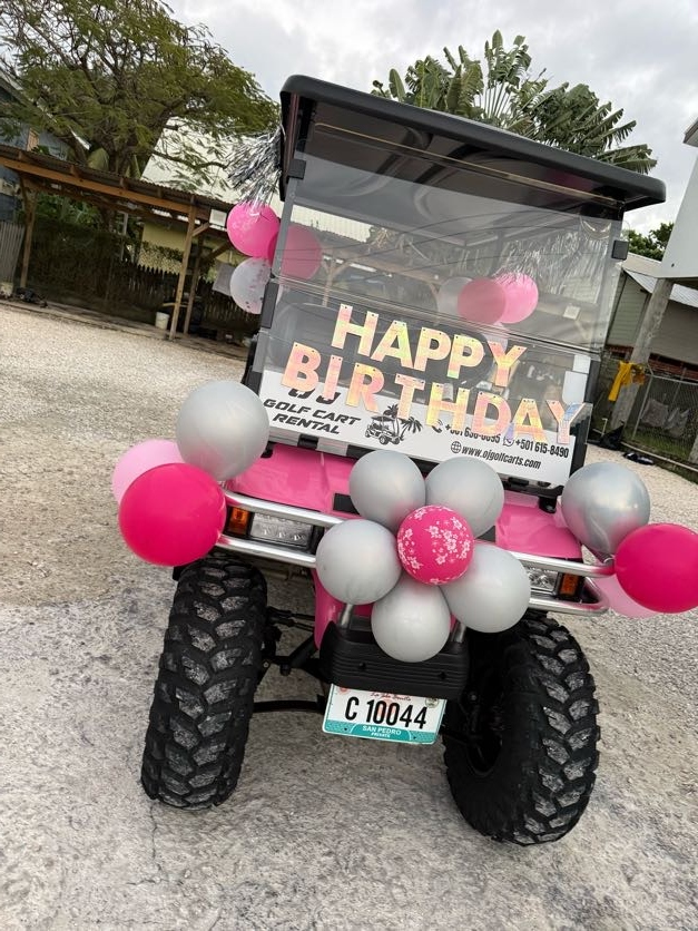 Pink golf cart rear view with Happy Birthday banner and pink silver balloon clusters in San Pedro Belize