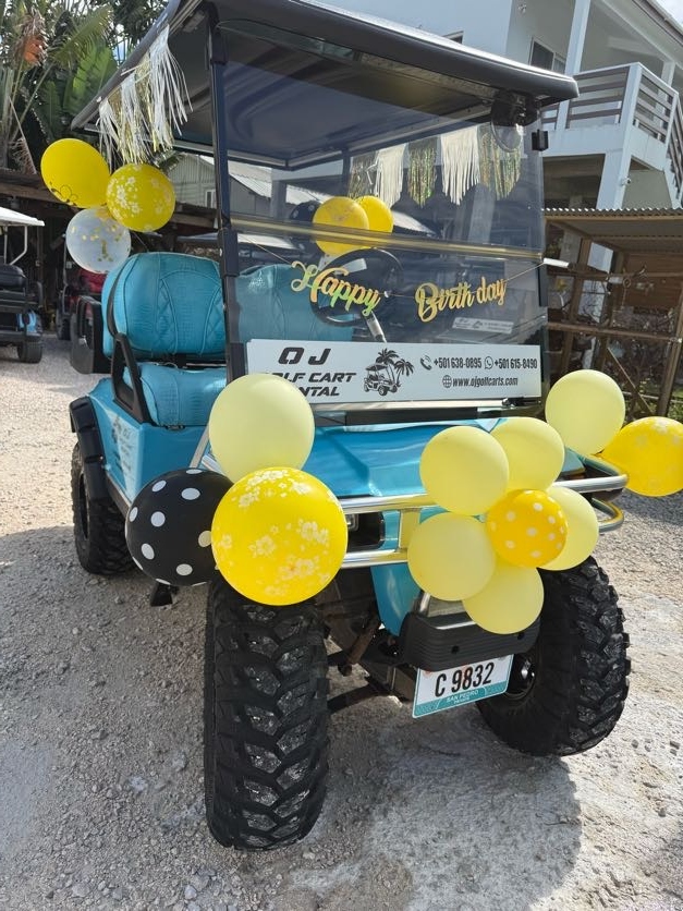 Teal golf cart with gold script Happy Birthday sign and yellow black polka dot balloon clusters in San Pedro Belize